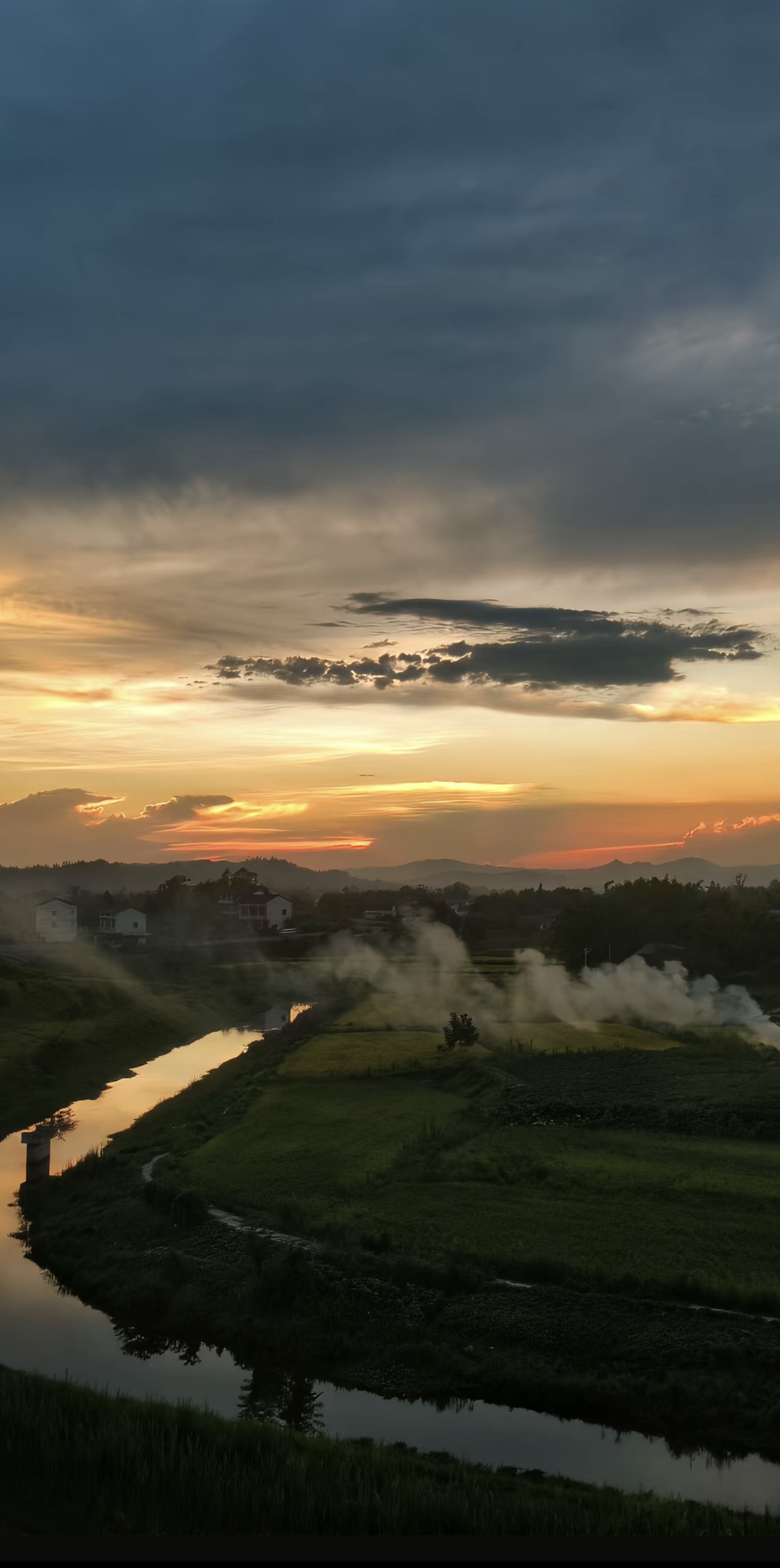 夕阳映照乡野、田地和蜿蜒河流